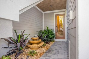 A narrow pathway leading to a door with a wooden ceiling and a small fountain. - Angel's View 4 Bedroom Home (Captiva)