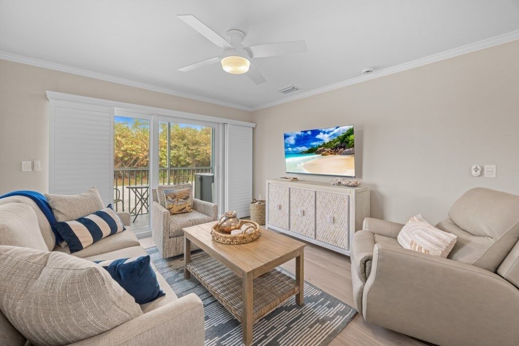 A living room with a sofa, armchair, coffee table, and TV.