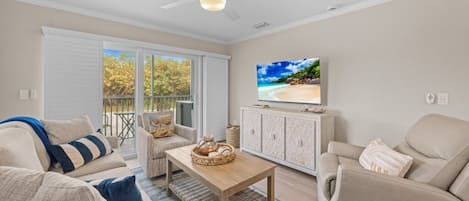 A living room with a sofa, armchair, coffee table, and TV.