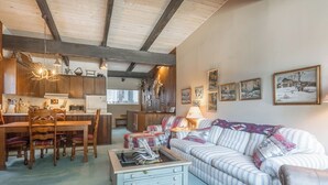 Ein gemütliches Wohnzimmer mit einem gestreiften Sofa, einem Couchtisch und einem Essbereich mit Holzeinrichtung.