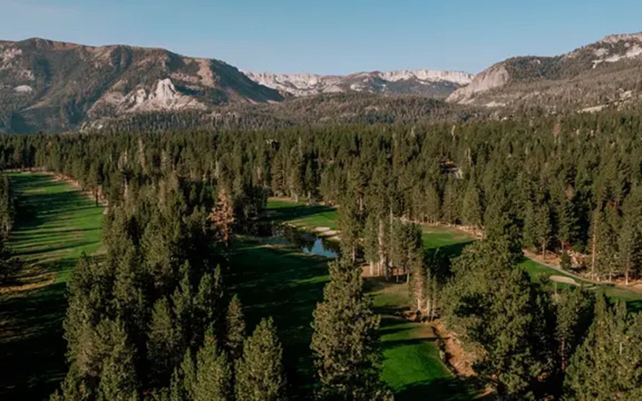 A mountainous landscape with dense forest and a golf course.