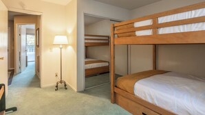 Ein Zimmer mit Etagenbetten, einer Lampe und einer Tür zu einem weiteren Raum.