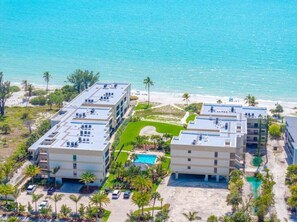 A multi-story hotel with a rooftop pool, surrounded by palm trees and a beach. - Kings Crown Unit 217 2 Bedroom Condo (Sanibel)