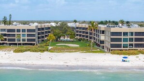 Un hotel frente a la playa con varias edificaciones, una playa arenosa y una vista despejada del océano.