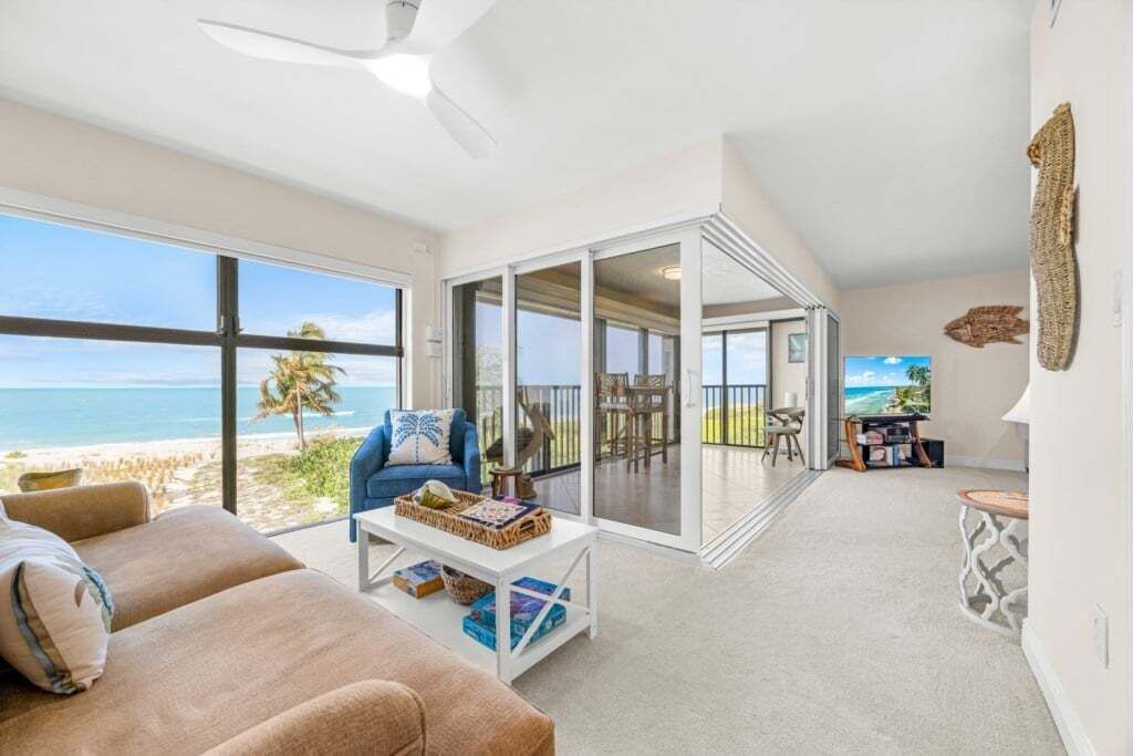 Un vaste espace de vie doté d’une grande fenêtre donnant sur une plage, d’un coin salon confortable et d’une vue sur l’océan.