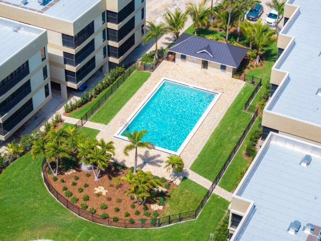 Una piscina circondata da palme e un prato ben curato, con edifici sullo sfondo.