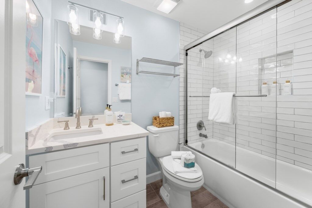 A modern bathroom with a glass-enclosed shower, a white sink with a marble countertop, and a toilet.