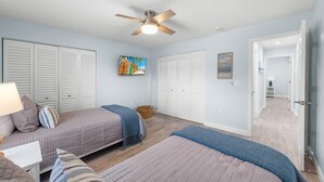 Un dormitorio con dos camas, un ventilador de techo y un cuadro en la pared.