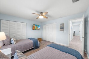 A bedroom with two beds, a ceiling fan, and a painting on the wall. - Seashells Unit 32 2 Bedroom Condo (Sanibel)