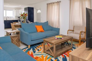 A modern living room with a blue sofa, a wooden coffee table, and a colorful rug. - Kaz Olivia 3 Bedroom Home (Gros Islet)