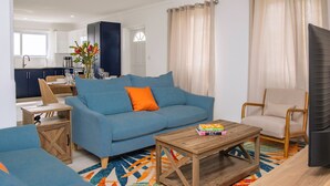 Uma sala de estar moderna com um sofá azul, uma mesa de centro de madeira e um tapete colorido.