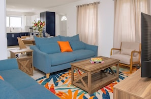 Ein modernes Wohnzimmer mit einem blauen Sofa, einem Holztisch und einem bunten Teppich.