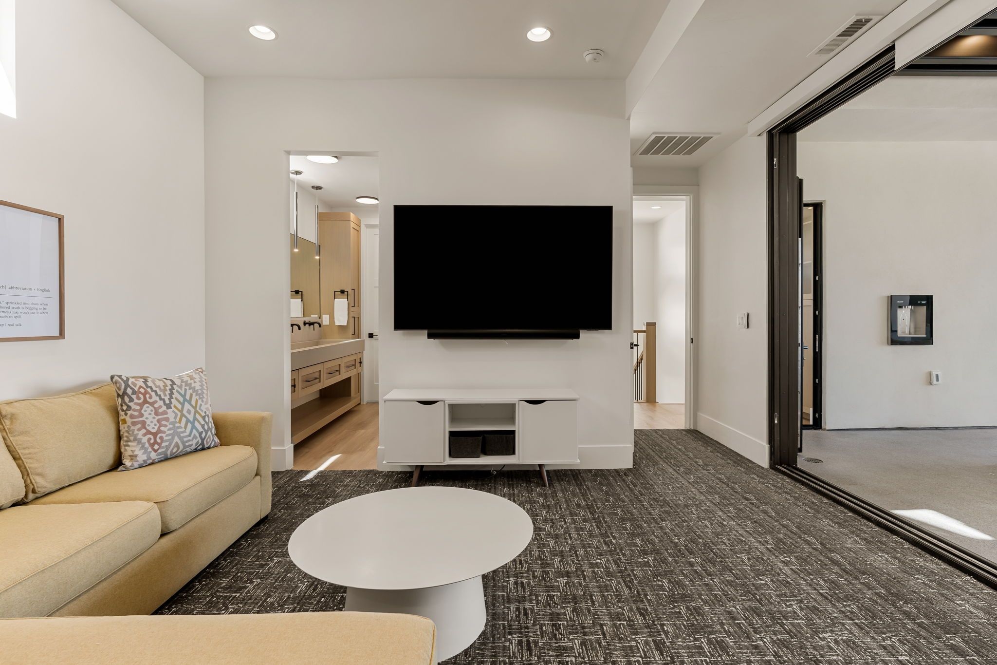 A modern living room with a flat-screen TV, a sofa, a coffee table, and a patterned carpet.