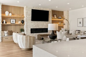 A modern living room with a stone wall, a flat-screen TV, a fireplace, and a sofa. - Paradise Palace 8 Bedroom Home (St. George)