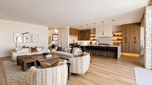 Una sala de estar moderna con un conjunto de sofá, una mesa de centro y una cocina con armarios de madera y una barra.