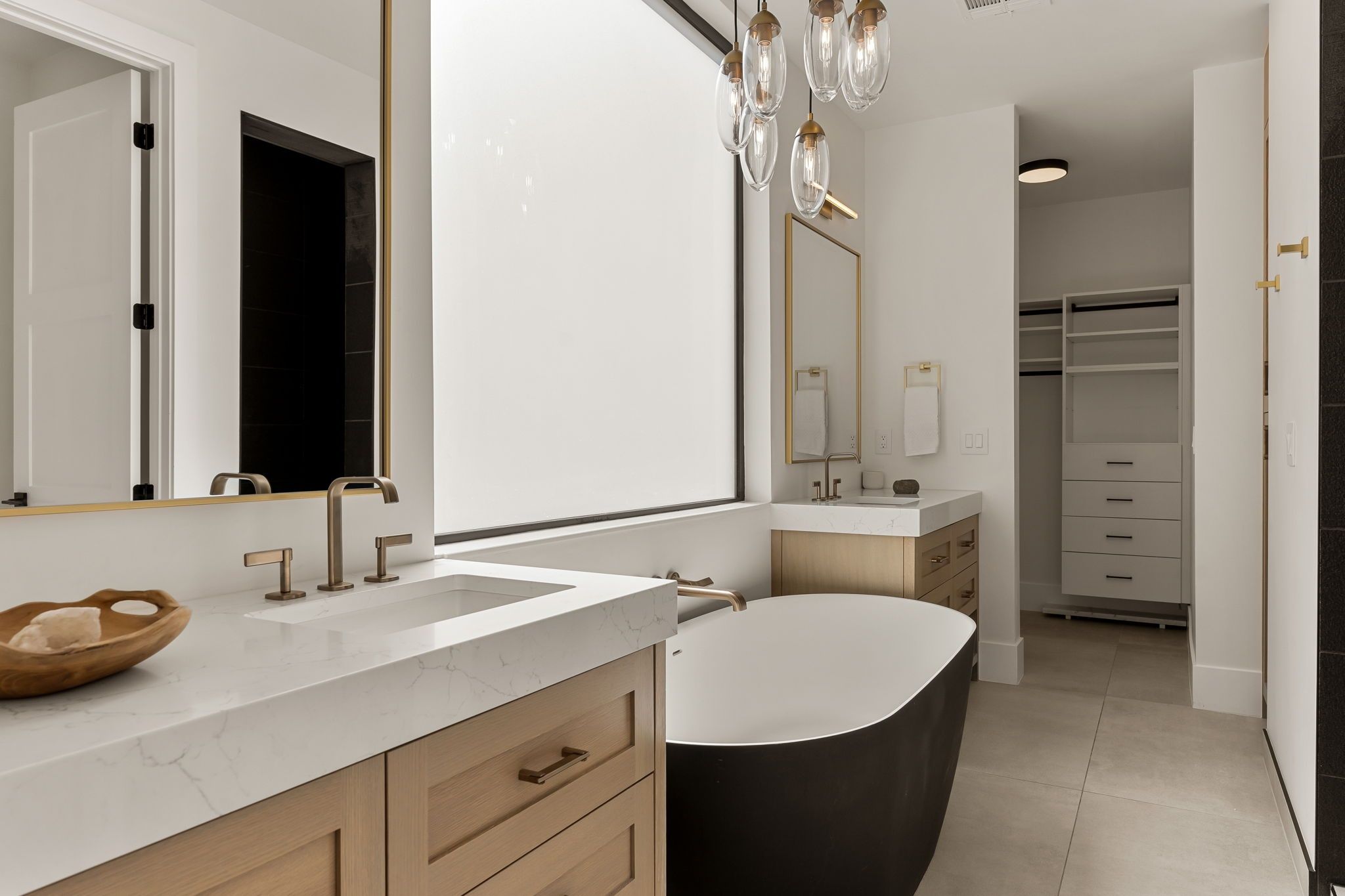 A modern bathroom with a freestanding bathtub, two sinks, and a large mirror.