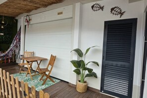A patio with a wooden table and chairs, a potted plant, and a closed garage door.