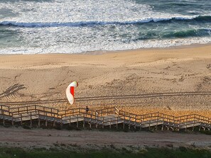 A beach with a wooden boardwalk leading to the water.