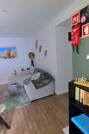 A modern living room with a sofa, a small table, a bookshelf, and a painting on the wall.