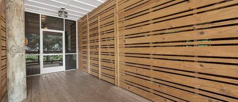 A wooden deck with a ceiling and a glass door leading outside.