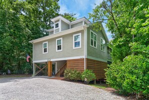 A two-story house with a covered porch and a gravel driveway. - Pawleys Hideaway On The Causeway 3 Bedroom Home (Pawleys Island)