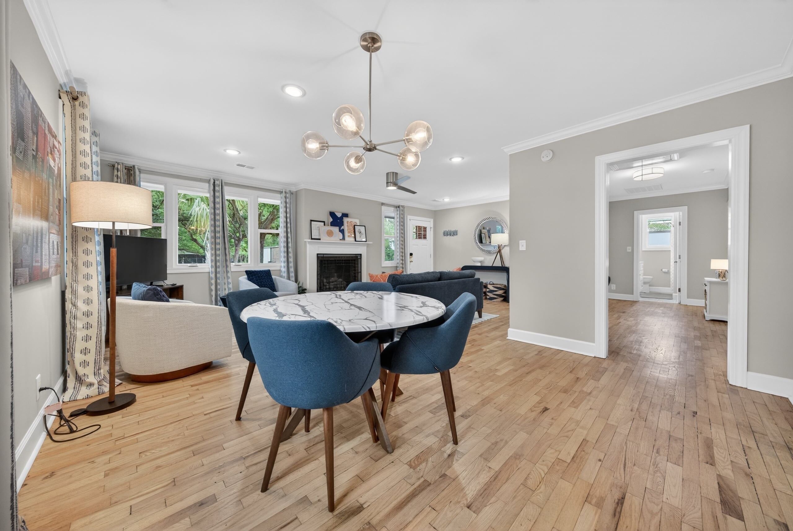 A spacious living room with a round table, blue chairs, a fireplace, and a large mirror.