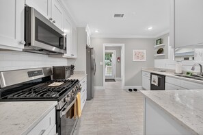Una cocina moderna con electrodomésticos de acero inoxidable, armarios blancos y encimera de mármol.