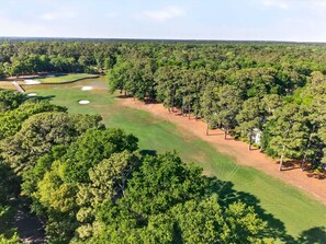 A golf course with sand bunkers, a clubhouse, and dense surrounding trees. - 127-3 Puttin On The Ritz 2 Bedroom Condo (Pawleys Island)