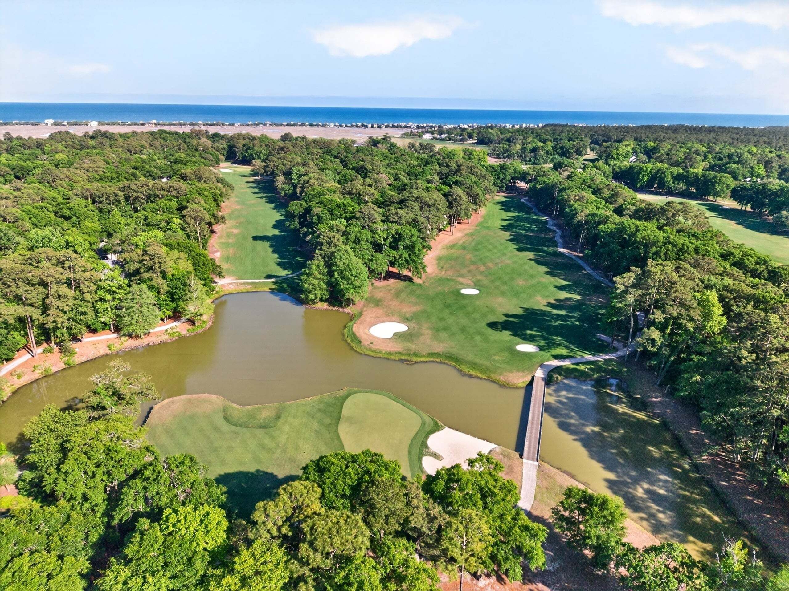 Ilmakuva golfkentästä, jossa on useita pelialueita, vesiesteitä ja silta.