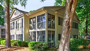 A two-story house with large windows, a covered porch, and a well-maintained garden. - 127-3 Puttin On The Ritz 2 Bedroom Condo (Pawleys Island)