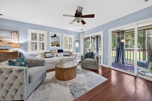 A spacious living room with a ceiling fan, large windows, and a view of the outdoors. - 127-3 Puttin On The Ritz 2 Bedroom Condo (Pawleys Island)