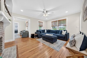 A spacious living room with a large sectional sofa, a ceiling fan, and a fireplace. - Charming Coastal Retreat 3 Bedroom Home (Georgetown)