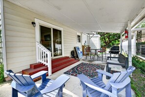 A covered porch with Adirondack chairs, a barbecue, and a small table. - Charming Coastal Retreat 3 Bedroom Home (Georgetown)