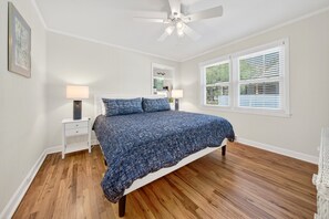 A bedroom with a bed, two bedside tables, a ceiling fan, and a window with blinds. - Charming Coastal Retreat 3 Bedroom Home (Georgetown)