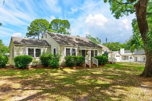 A single-story house with a front porch, a small front yard, and a tree to the right. - Charming Coastal Retreat 3 Bedroom Home (Georgetown)
