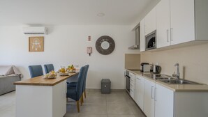 A modern kitchen with white cabinets, a wooden countertop, and a dining area with blue chairs. - #412 Apartment with Pool | 1BR | Near Oura & the Beaches (Albufeira)
