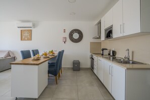 Eine moderne Küche mit weißen Schränken, einer Holzarbeitsplatte und einem Essbereich mit blauen Stühlen.