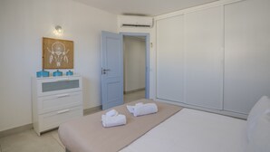 A bedroom with a bed, a dresser, a wardrobe, a door, and a wall art piece. - #412 Apartment with Pool | 1BR | Near Oura & the Beaches (Albufeira)