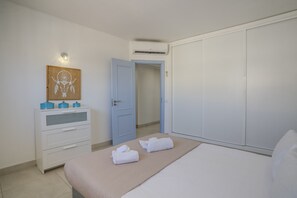 Ein Schlafzimmer mit Bett, Schminktisch, Kleiderschrank, Tür und einem Wandbild.
