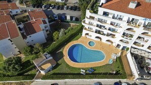An aerial view of a hotel with a swimming pool, multiple balconies, and a parking lot. - #412 Apartment with Pool | 1BR | Near Oura & the Beaches (Albufeira)