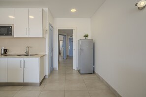 A modern kitchen with white cabinets, a built-in microwave, a kettle, and a refrigerator. - #412 Apartment with Pool | 1BR | Near Oura & the Beaches (Albufeira)