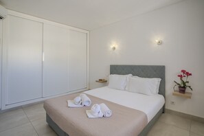 A hotel room with a bed, a wardrobe, a nightstand, and a wall-mounted shelf with a potted plant. - #412 Apartment with Pool | 1BR | Near Oura & the Beaches (Albufeira)