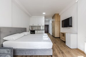 A modern hotel room with a large bed, a small kitchenette, a TV mounted on the wall, and a wooden cabinet. - Sea Stay Studio Durr s Waterfront (Durrës)