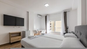 A hotel room with a bed, a desk, a chair, a flat-screen TV, and a window with curtains. - Sea Stay Studio Durr s Waterfront (Durrës)
