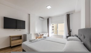 A hotel room with a bed, a desk, a chair, a flat-screen TV, and a window with curtains. - Sea Stay Studio Durr s Waterfront (Durrës)