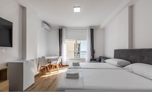 A modern hotel room with a bed, a desk, a chair, and a TV. - Sea Stay Studio Durr s Waterfront (Durrës)
