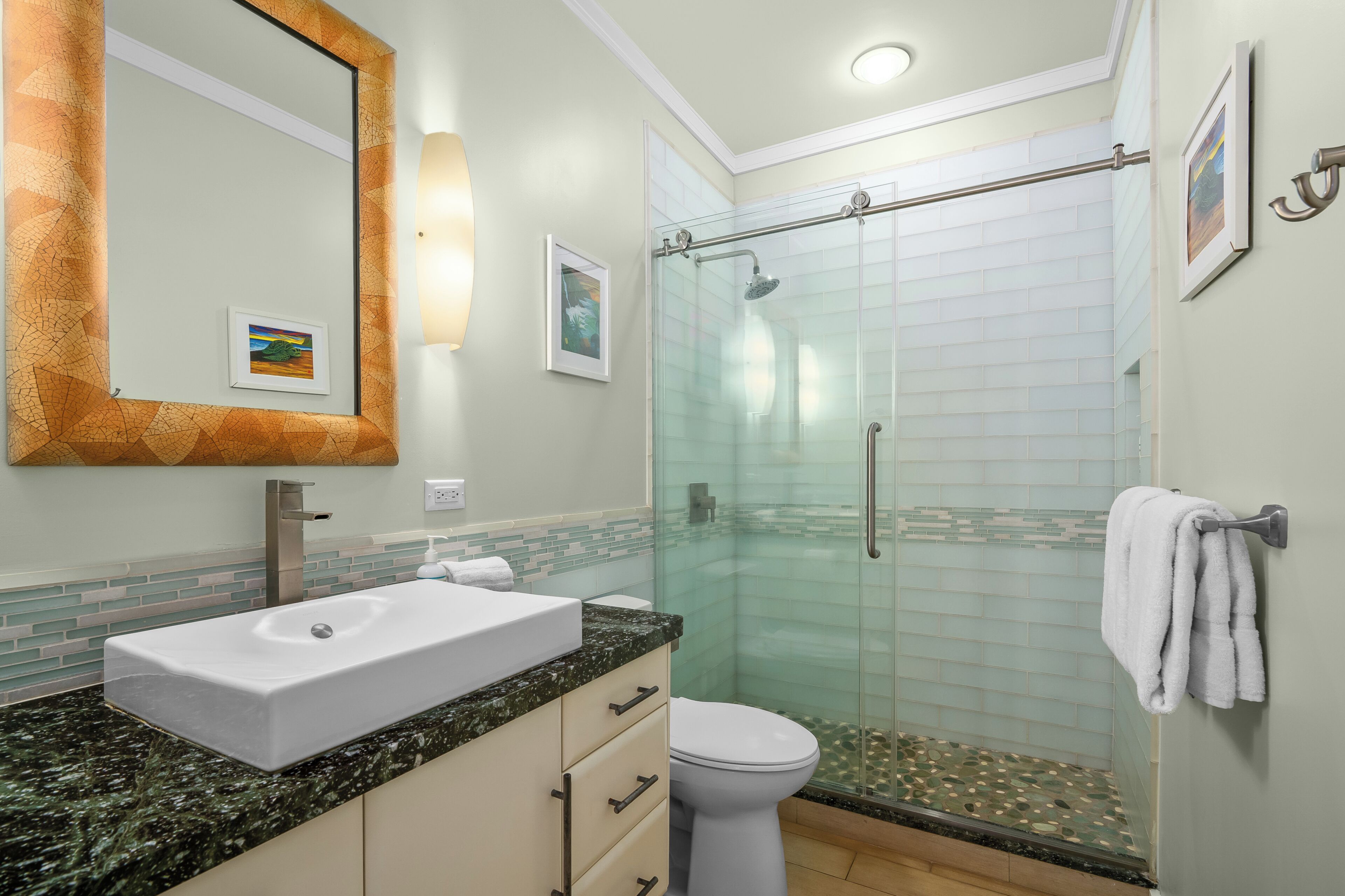 A bathroom with a white sink, a glass shower enclosure, and a large mirror with a decorative frame.
