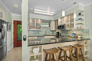 Eine moderne Küche mit einer Granit Arbeitsplatte, Edelstahlgeräten und Holzbarhocker.