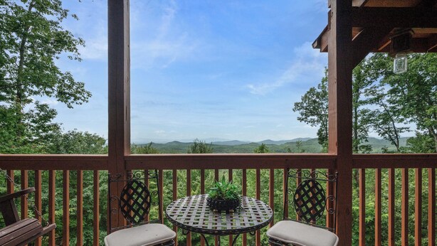 Un balcon avec une table et deux chaises, donnant sur un paysage pittoresque.