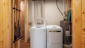 Une buanderie équipée de deux machines à laver blanches, d’un sèche-linge gris et d’un chauffe-eau.